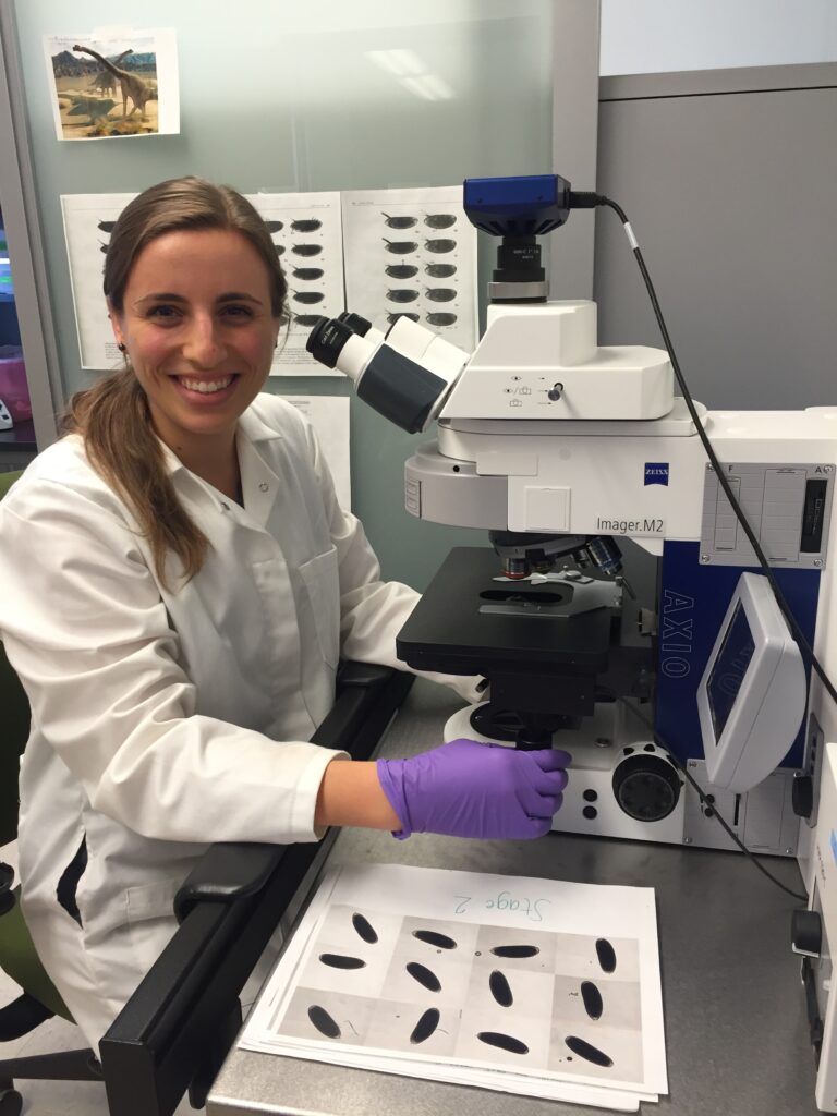 Dr. Cartwright sitting beside a microscope.