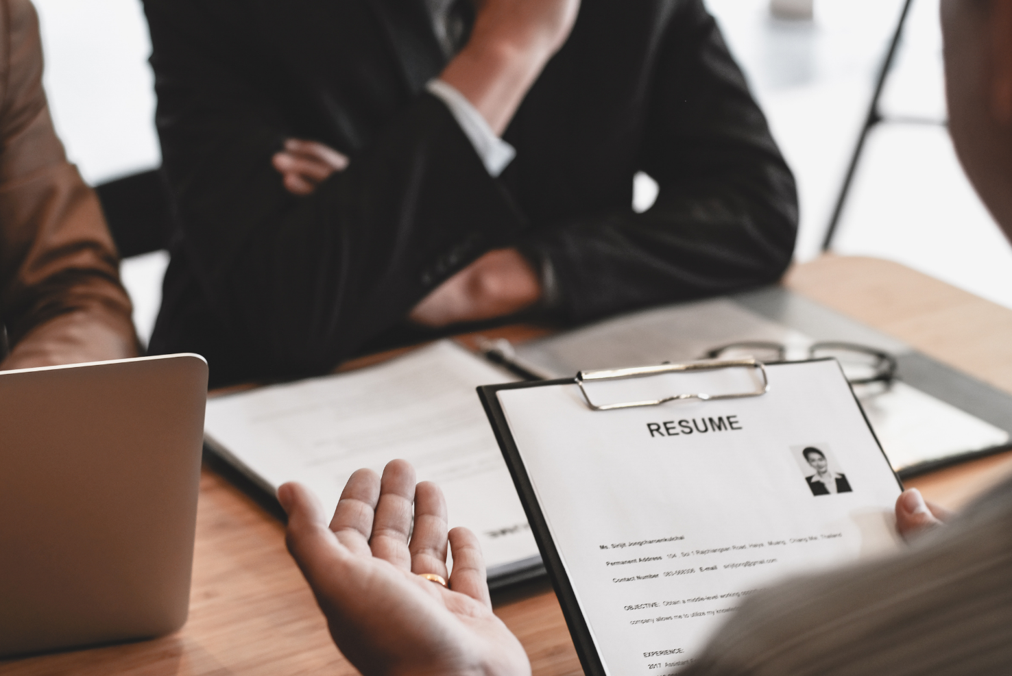 Clipboard with resume and person wearing suit across from table